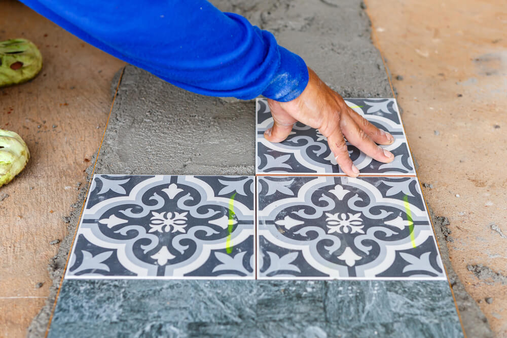 a tiler laying some pattern tiles outside of a house with tile grout down ready to be used